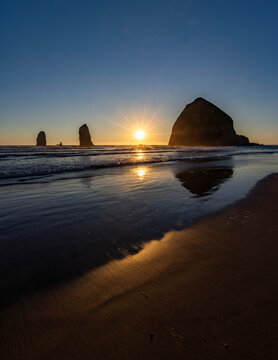 USA, Oregon, Sun setting behind haystack rock on Cannon Beach