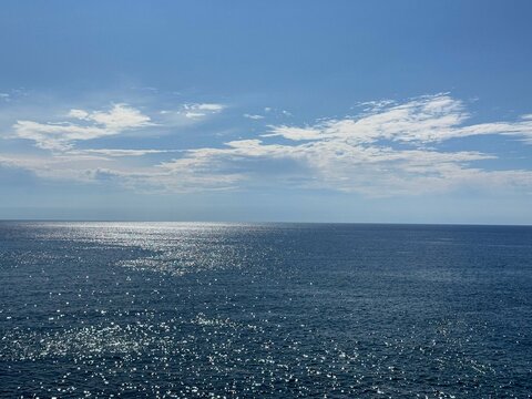 Open sea blue calm water with glints and sunny sky.