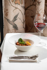 Spaghetti bolognese with rich meat sauce basil and grated parmesan served on white plate with red wine