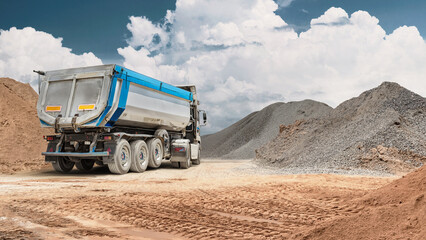 At a construction site, a large dump truck carries sand in its back. Heavy equipment is used to move materials such as gravel and soil © Anoo