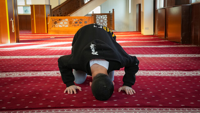 Muslim man in sujud prostration during prayer at a mosque. Young Muslim scholar performing Sajda in spiritual devotion. male in traditional prayer posture on a mosque carpet.