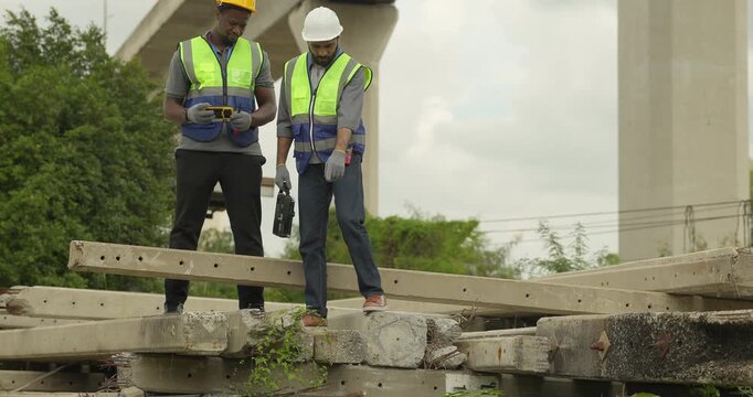 Railway engineer and technician conduct quality control material inspection on concrete pier segments and construction waste. Checking structural condition for safe site housekeeping and asset reuse.
