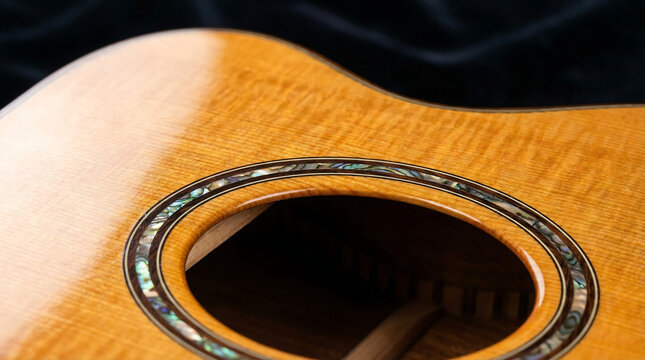 Exquisite closeup of an acoustic guitar soundhole showcasing detailed abalone inlay and finely grained wood
