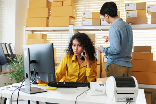 Female Small Business owner, warehouse stock manager Reviewing Order Dashboard on Computer working in office while phone call to check and confirmation order detail preparing to ship.