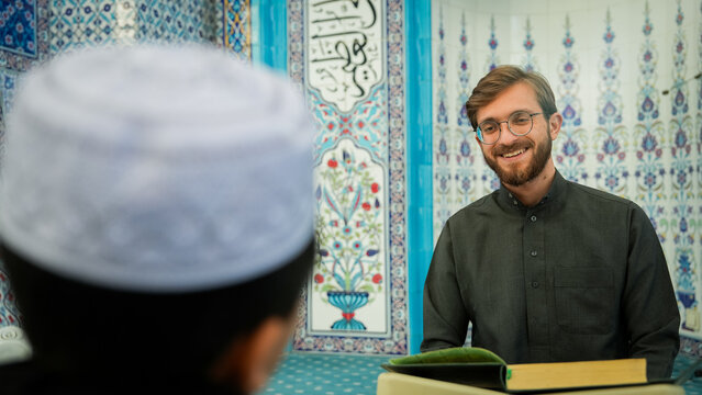 Muslim children chatting and laughing with their teacher in mosque. Fasting Muslims worshipping and bonding at masjid during Ramadan. Religious education and Islamic community atmosphere.
