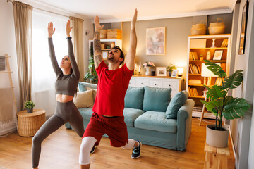 Obraz premium Couple doing yoga while working out at home