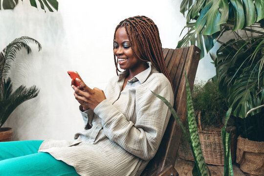 A joyful woman uses her smartphone surrounded by lush greenery