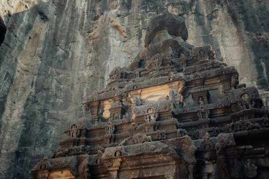 Verul, India - 27 December 2025: View of the Kailasa Temple's intricate carvings contrasting against the rough, towering rock face, bathed in the warm glow of the setting sun.