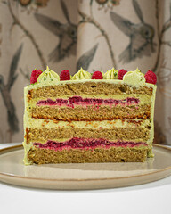 Pistachio and raspberry layer cake with creamy filling and fresh berries served on elegant plate