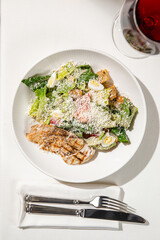 Caesar salad with grilled chicken romaine lettuce parmesan cheese and creamy dressing served on white plate