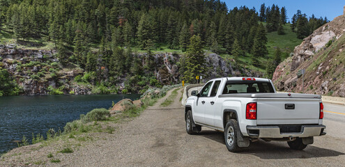Fototapeta premium Pickup truck on the beautiful road along the mountain river and forest.