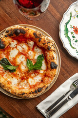 Classic pizza margherita with melted mozzarella tomato sauce and fresh basil served with red wine