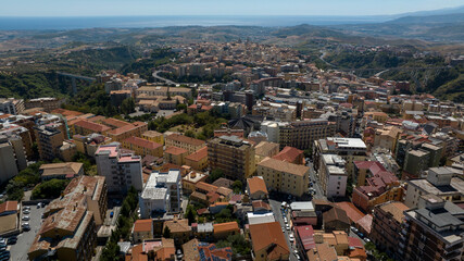 Fototapeta premium Panoramic aerial view of the city of Catanzaro, capital of the Calabria region in southern Italy. In the foreground are the town's houses, buildings, and rooftops. The Ionian Sea is on the horizon.