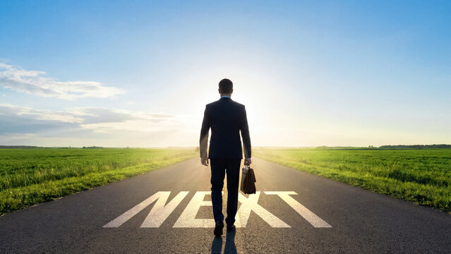 Businessman walking on road towards the future with the word 'next' painted on asphalt, leadership progression and career advancement on an open highway, business journey forward concept
