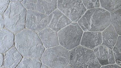 Natural grey stamped concrete or stone texture with a random flagstone pattern. Rough, rugged surface. Gray hexagonal printed concrete texture background. © Kawee