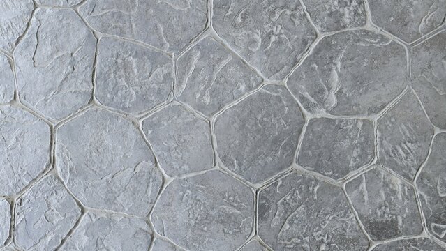 Natural grey stamped concrete or stone texture with a random flagstone pattern. Rough, rugged surface. Gray hexagonal printed concrete texture background.