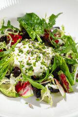 Fresh restaurant style beet and zucchini salad with mixed greens cheese and herbs served on white plate