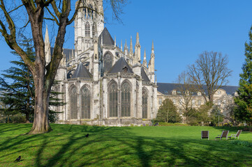 Fototapeta premium Saint Ouen Abbey Church building seen from lawn under clear blue sky, church standing tall in spring sunlight, church stone details and bright grass creating peaceful historic city scene outdoors