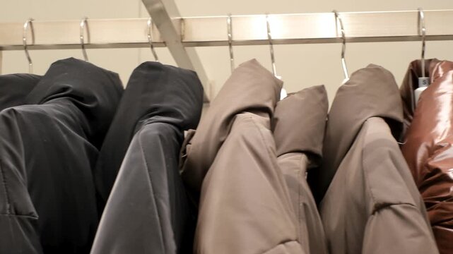 Winter down jackets hanging on hangers in the store close-up, side view.