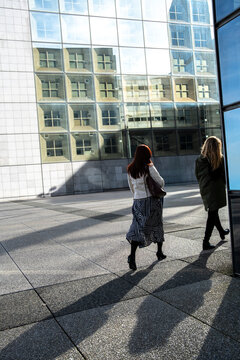 Pedestrian shadow crosses a plaza in architecture of corporate business finance office district in Paris La Defense France during bright daylight