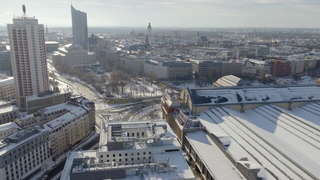 Panoramic view over snowy Leipzig, from Augustusplatz to the main station. Iconic landmarks like the City Tower and the Opera House define the white cityscape under a clear blue sky.
