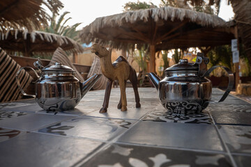 Tradycyjny metalowy czajnik i dekoracje egipskie na tarasie restauracji – letni relaks na świeżym powietrzu. © siwyk