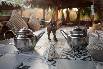 Tradycyjny metalowy czajnik i dekoracje egipskie na tarasie restauracji – letni relaks na świeżym powietrzu. © siwyk