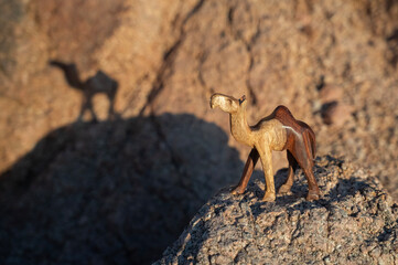 Rzeźba wielbłąda na tle skał i błękitnego nieba – pustynny krajobraz w słoneczny dzień © siwyk