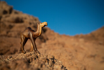 Rzeźba wielbłąda na tle skał i błękitnego nieba – pustynny krajobraz w słoneczny dzień © siwyk