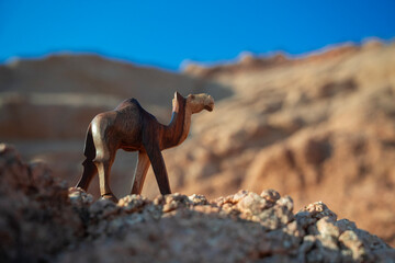 Rzeźba wielbłąda na tle skał i błękitnego nieba – pustynny krajobraz w słoneczny dzień © siwyk