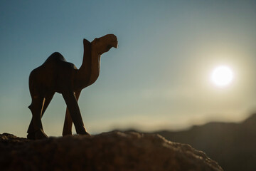 Rzeźba wielbłąda na tle skał i błękitnego nieba – pustynny krajobraz w słoneczny dzień © siwyk