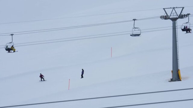Snowboarders descending snowy mountain under chairlift in klosters davos