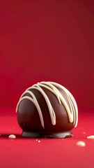 Obraz premium Gourmet chocolate truffle with white chocolate drizzle on deep red background, perfect for dessert advertising or confectionery marketing
