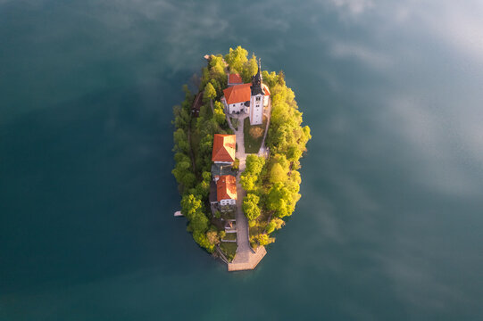 Aerial view of the island with its iconic church and vibrant green trees surrounded by the tranquil waters of Lake Bled, Bled, Radovljica, Slovenia.