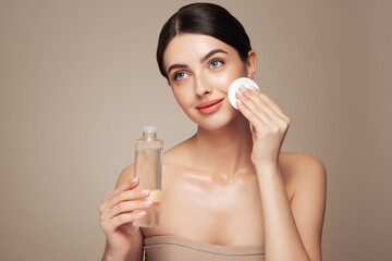 Young girl holds cotton pad while cleansing face with cosmetic milk. Skin care removal of makeup cleansing. Basic facial skin care © Oleg Gekman