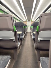Empty modern passenger train interior with rows of seats, central aisle, and overhead lighting, showing clean, comfortable public transport design. Uk 2026