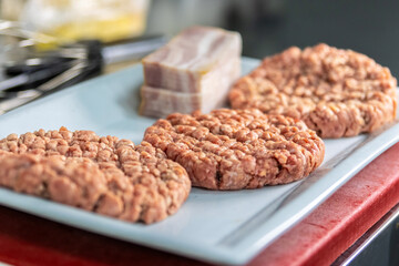 Fototapeta premium Preparing raw beef burger patties with bacon slices
