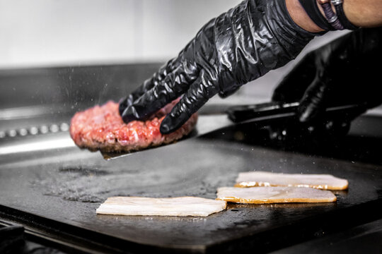 Chef cooking angus beef burger and bacon on grill