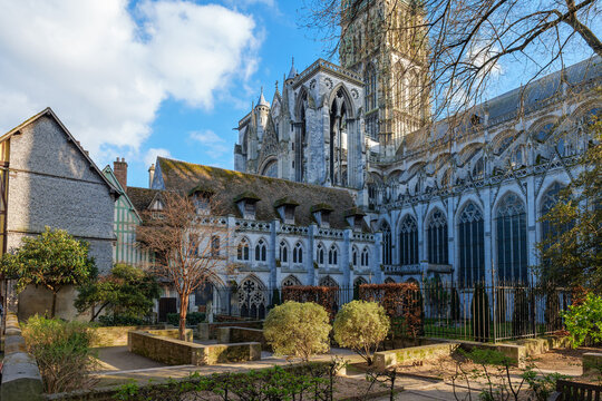 Rouen Cathedral seen from Albane Gardens in spring with fresh green leaves and soft sunlight, cathedral stone facade glowing under blue sky, cathedral framed by trees and park views outdoors