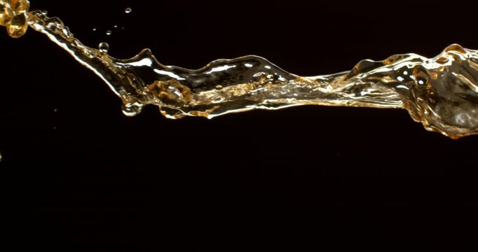 Super slow motion oil splash forming soft waving shapes on black background, high-speed liquid motion, glossy texture, clean minimal look, cinematic lighting, premium food and cosmetic concept