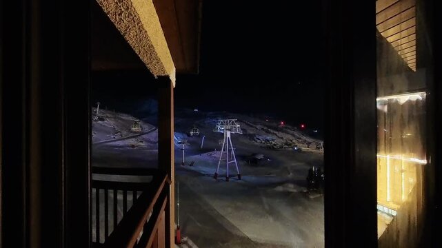 Peaceful Night View of a Ski Resort with Illuminated Slopes and Silent Ski Lifts