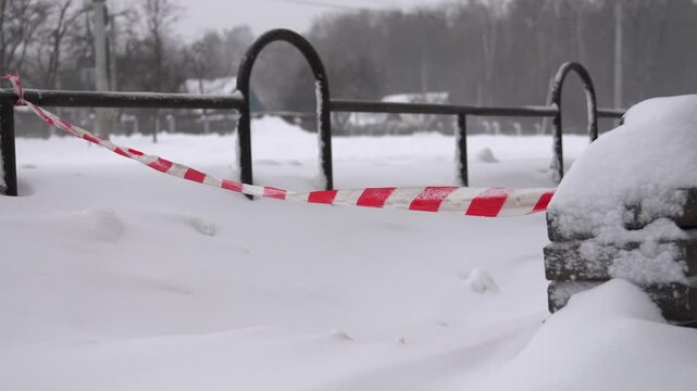 Barrier signals danger, Snowcovered recreational area cordoned off for safety reasons after storm, Temporary red barrier indicates hazard and closure across winter landscape after inclement weather