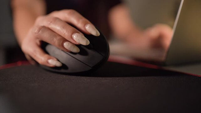 Close-up of woman's hand controlling a special vertical mouse on a pad, ergonomic design for comfortable long-term computer use.