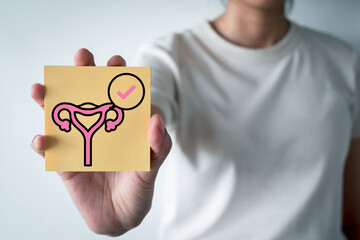 Gynecology health checkup and cancer screening result. Woman hand holding paper note with uterus organ icon and tick sign. Concept of healthy reproductive system, fertility,PCOS and period cycle.