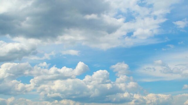 A vast expanse of bright blue sky dotted with fluffy white clouds.Several clouds of varying sizes are scattered across the blue background.This evokes a sense of open space and a peaceful atmosphere