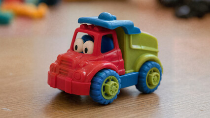 Fototapeta premium Colorful toy truck with cartoon eyes on wooden floor