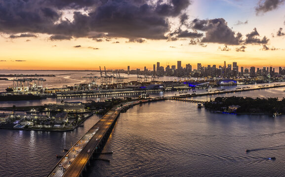 Aerial view of the MacArthur Causeway stretching towards the glittering skyline of Miami under a fiery sunset canvas, South Beach, Miami Beach, Florida, United States.