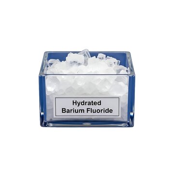 A transparent glass container holding white hydrated barium fluoride crystals on a white surface viewed from directly above