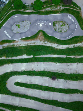 Aerial view of winding paths cut through green grass, a playground with the name "Arinsal" visible, Arinsal, Andorra.