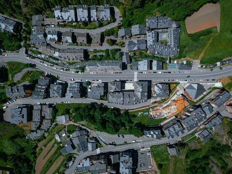 Aerial view of buildings with grey rooftops lining a street, nestled amidst vibrant green patches, Arinsal, La Massana, Andorra.